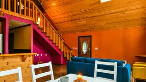 Una habitación acogedora con una escalera de madera, un sofá azul y una mesa blanca con un ordenador portátil y una vela.