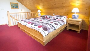 Ein Zimmer mit Holzvertäfelung, einem Bett, zwei Nachttischen und einer Wandlampe.
