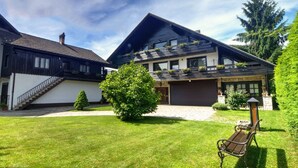 Ein zweistöckiges Haus mit geneigtem Dach, einer angebauten Garage und einem gepflegten Rasen.