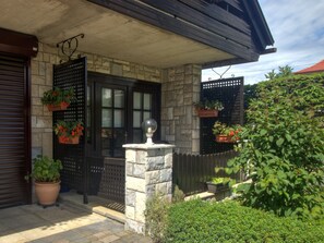 A stone house with a black door, potted plants, and a small garden.