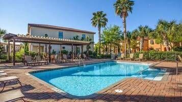 Relax by the pool surrounded by a patio and palm trees.