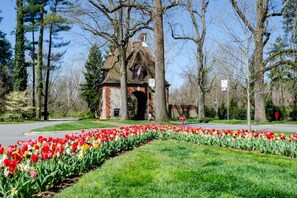 Un bâtiment historique doté d’une arche en briques, entouré d’un jardin bien entretenu où poussent de nombreuses variétés de tulipes.