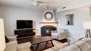Una sala de estar con chimenea, televisor y ventilador de techo.