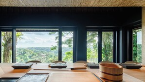 A dining area with a wooden table, chopsticks, and a wooden bowl. - The Sayan House (Ubud)