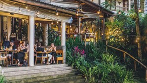 An outdoor seating area with tables and chairs, surrounded by lush greenery and plants. - The Sayan House (Ubud)