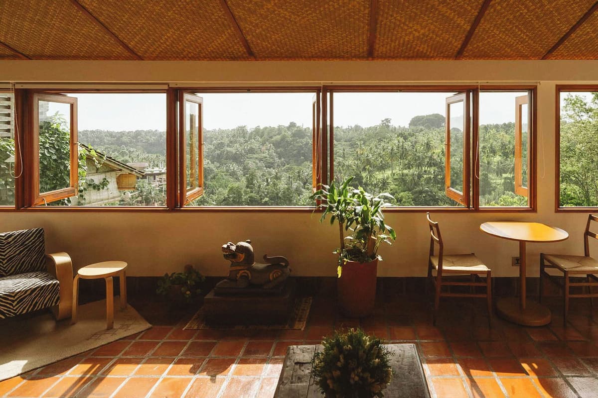 A room with large windows, a sofa, a small table, and a chair.