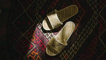 A pair of woven slippers on a patterned carpet.