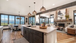 A spacious kitchen with a large island, dark cabinetry, and a view of the outdoors. - Amazing Views @ Luxury Home, Outdoor Fireplace + Game Room (Grand Lake)