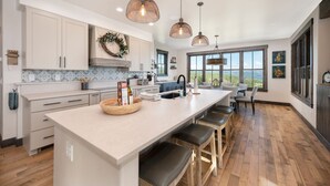 A modern kitchen with a large island, pendant lights, and a view of the outdoors. - Amazing Views @ Luxury Home, Outdoor Fireplace + Game Room (Grand Lake)
