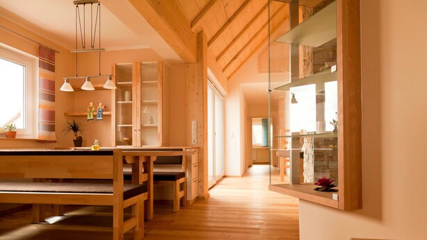 Una cocina amplia con suelo de madera, una zona de comedor con bancos y un gran ventanal.