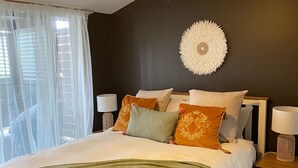 Ein Schlafzimmer mit einem Bett, einem Deckenventilator, einer Wanduhr und einem Nachttisch mit Lampe.