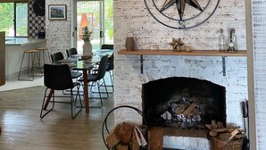 Ein modernes Interieur mit freiliegenden Ziegelwänden, einem Kamin und einem Essbereich mit großem Fenster.