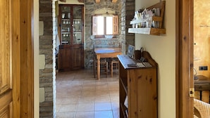 Una cocina rústica con un arco de piedra, armarios de madera y suelo de baldosas.