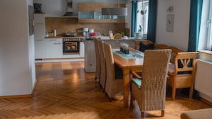 Una cucina moderna con mobili in legno, un'isola centrale e un'area pranzo con sedie in vimini.
