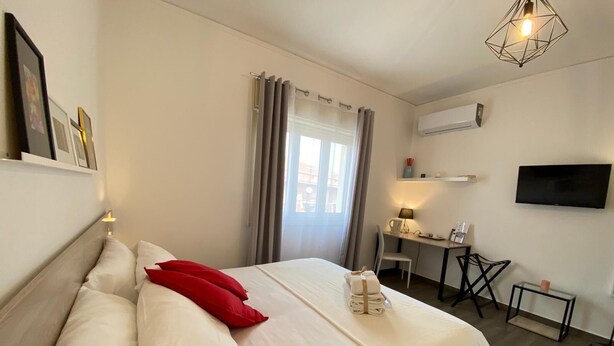 A neatly arranged bedroom with a bed, a desk, and a TV. - Economy Double Room Standard Rate (Cefalù)