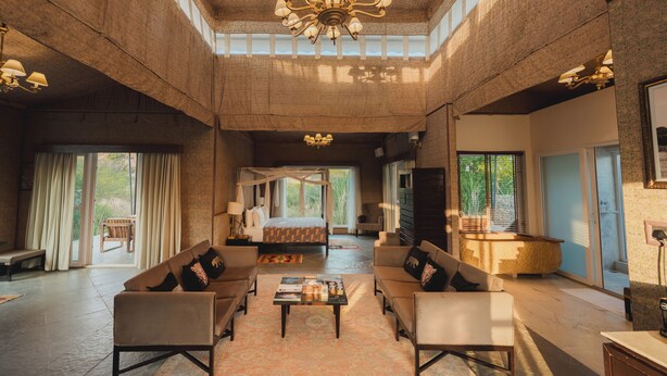A spacious living area with a large bed, sofas, a coffee table, and a chandelier. - Brij Pola, Jawai - Luxury Jungle Camp with Private Pools (Bali)