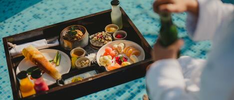 A tray with various food items including bread, fruits, and condiments, held by a person.