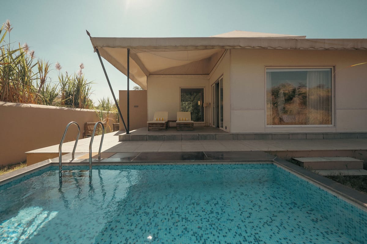Ein moderner Poolbereich im Freien mit überdachter Lounge und freiem Blick auf die umliegende Landschaft.