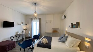 A modern hotel room with a bed, a desk, a chair, and a TV.