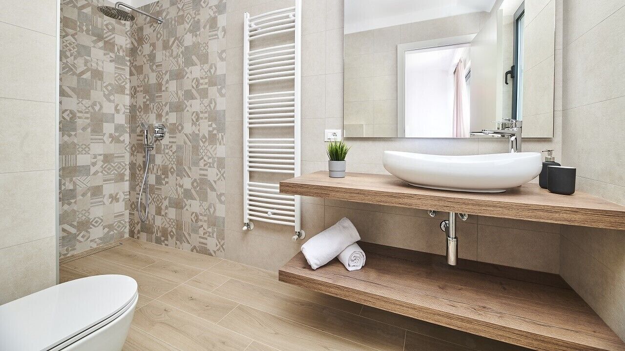A modern bathroom with a shower, a toilet, a sink with a mirror, and a towel rack.