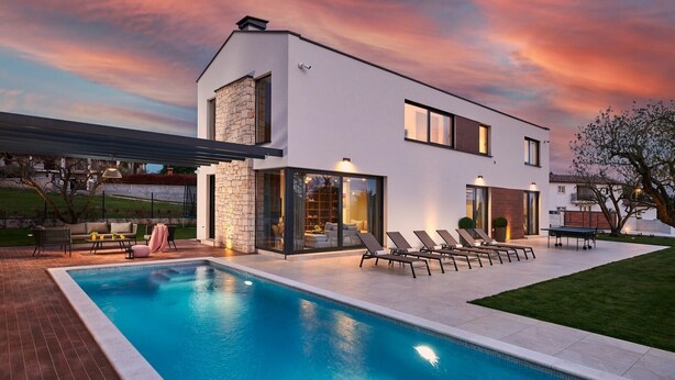 Uma casa moderna de dois andares com piscina, área de estar externa e um gramado bem cuidado.