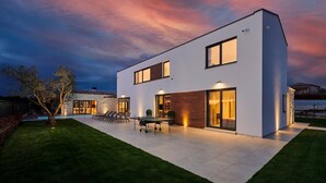 Uma casa moderna de dois andares com piscina, área de estar ao ar livre e gramado bem cuidado.