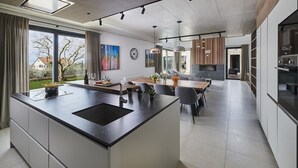 Uma cozinha moderna com uma ilha grande, área de refeições e eletrodomésticos embutidos.
