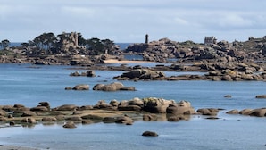 Un paisaje costero con costas rocosas, un faro y edificios históricos.
