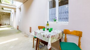 Un comedor con una mesa dispuesta para dos personas, una botella de vino y vasos verdes.