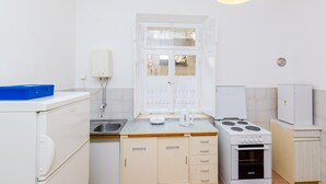 Una cocina compacta con estufa, pileta y ventana.