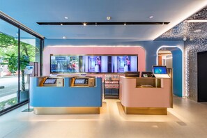 A reception area with a digital display, a self-service kiosk, and a seating area. - Hanting Hotel (Shanghai)
