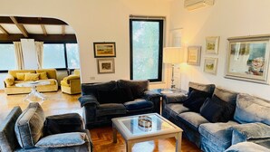 Ein geräumiges Wohnzimmer mit mehreren Sitzbereichen, darunter Sofas und Sessel, die um einen zentralen Couchtisch angeordnet sind.