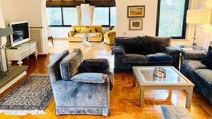 Ein geräumiges Wohnzimmer mit Holzboden, einem Fernseher und zwei Sofas.