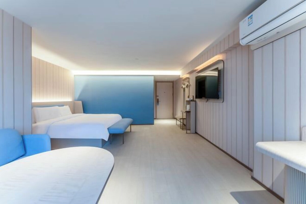 Quarto de hotel com duas camas, televisão e ar condicionado.