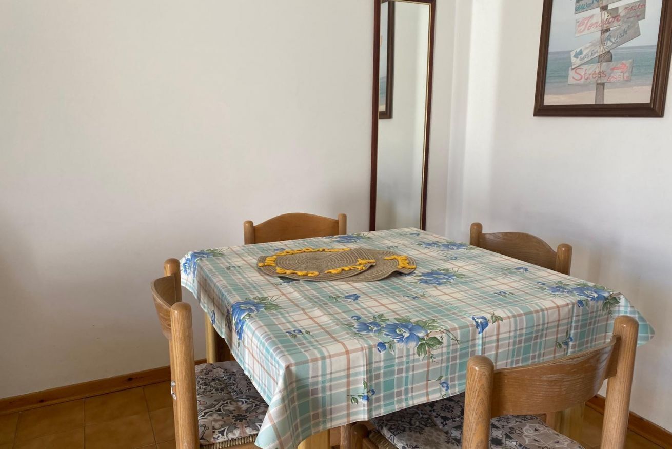 Un tavolo da pranzo con tovaglia floreale, sedie di legno e uno specchio a parete.