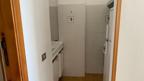 A narrow hallway with a white sink, a small cabinet, and a tiled wall.
