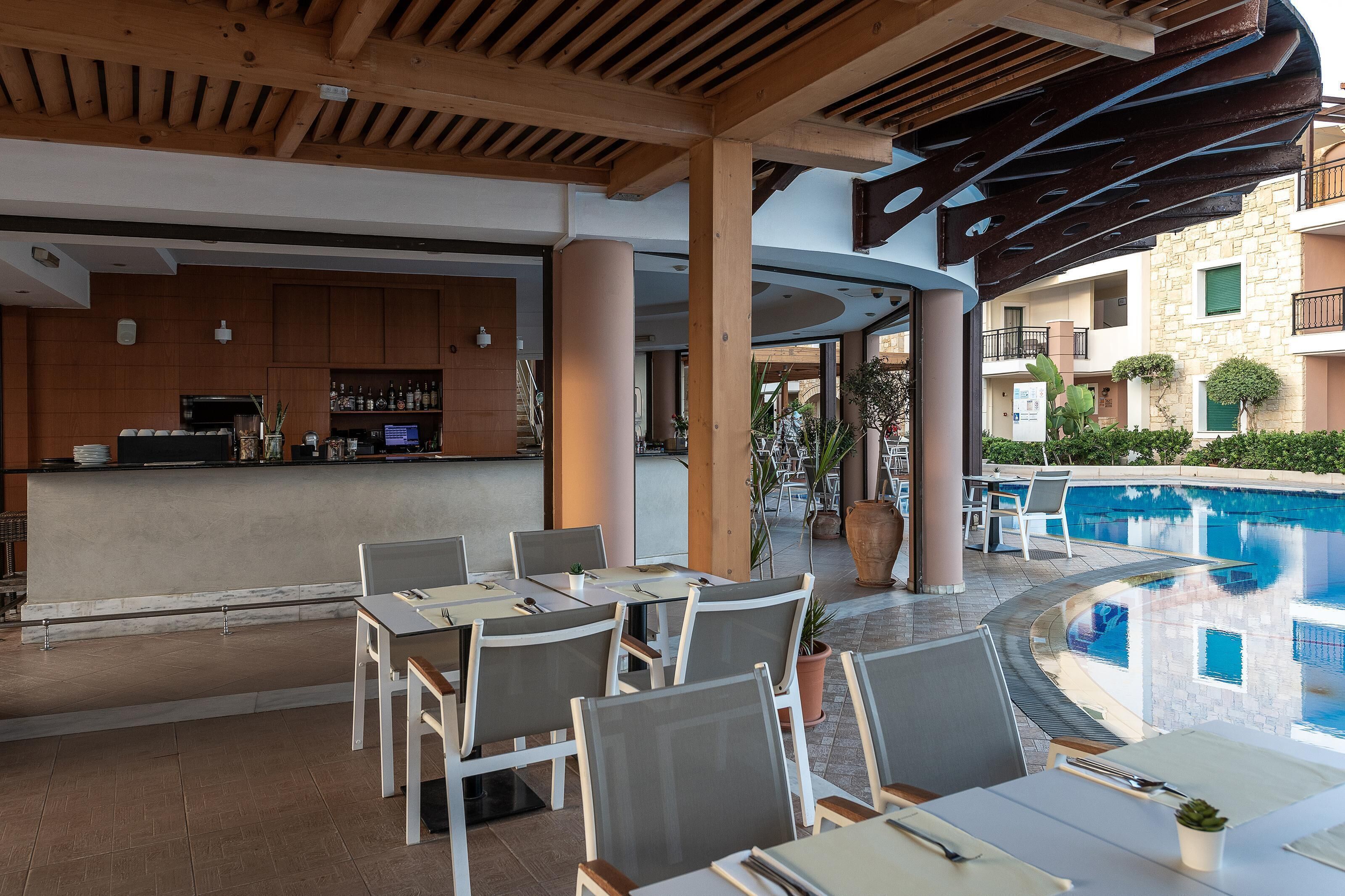 Ein Essbereich am Pool mit Tischen, Stühlen und einer Bar, sowie ein Schwimmbecken.
