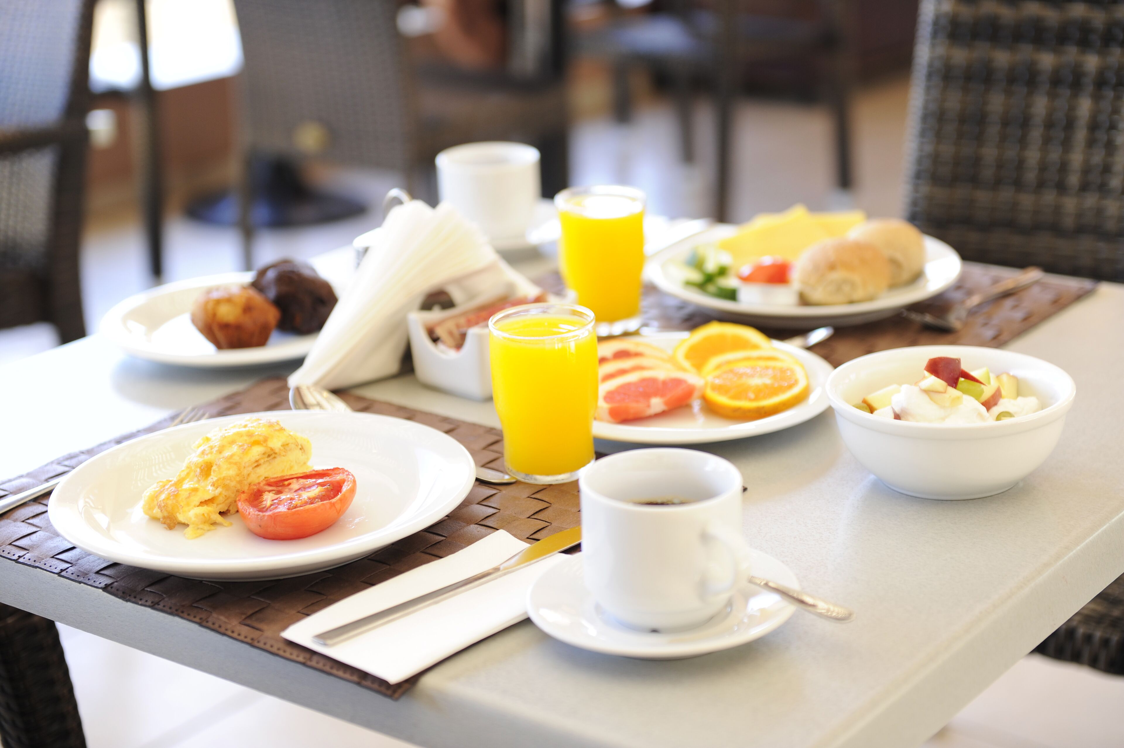 Ett frukostbord med tallrikar fulla av mat, ett glas apelsinjuice och en kopp kaffe.