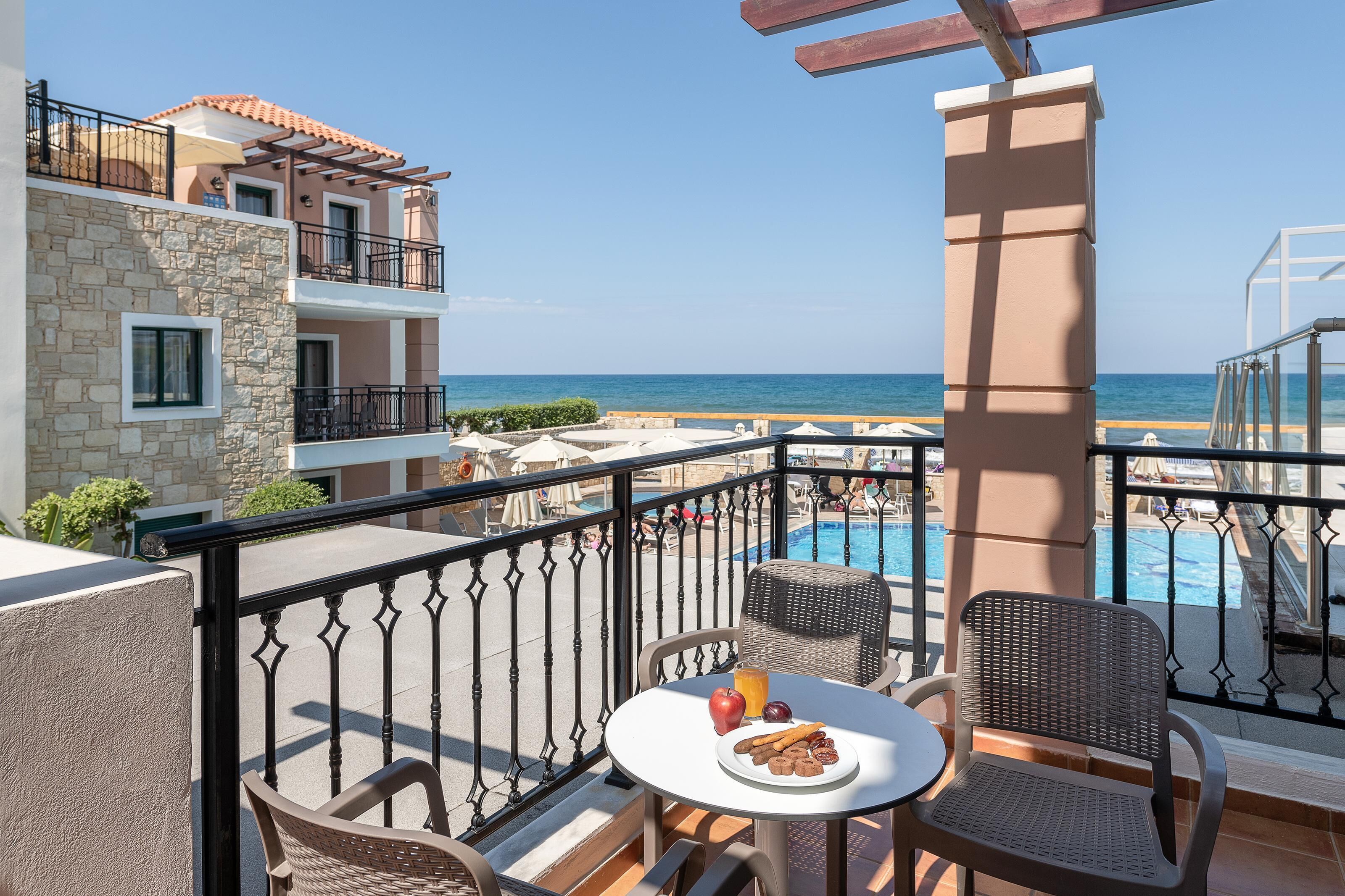 Un balcone con un tavolo apparecchiato per la colazione, vista su una piscina e il mare.