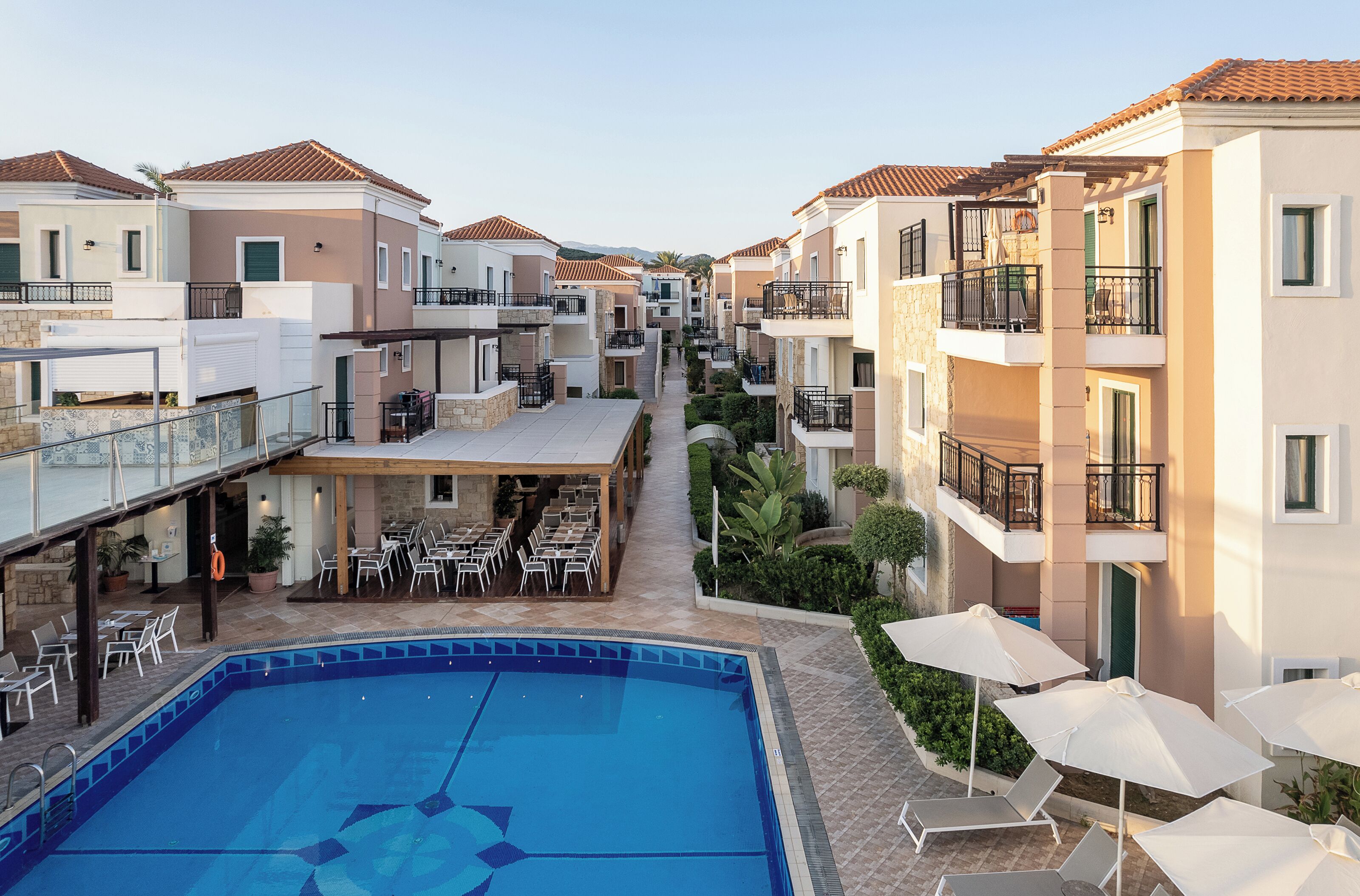 Un hotel con piscina, mobiliario exterior y varios balcones.