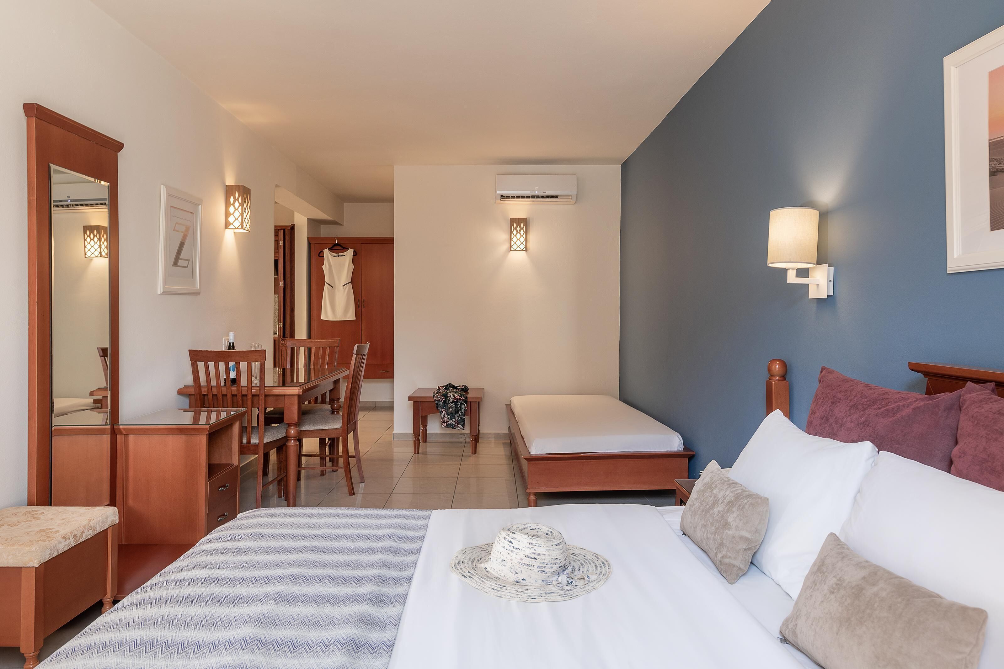 Une chambre d’hôtel comprenant un lit, une table de chevet, une lampe, une armoire et un bureau avec des chaises.