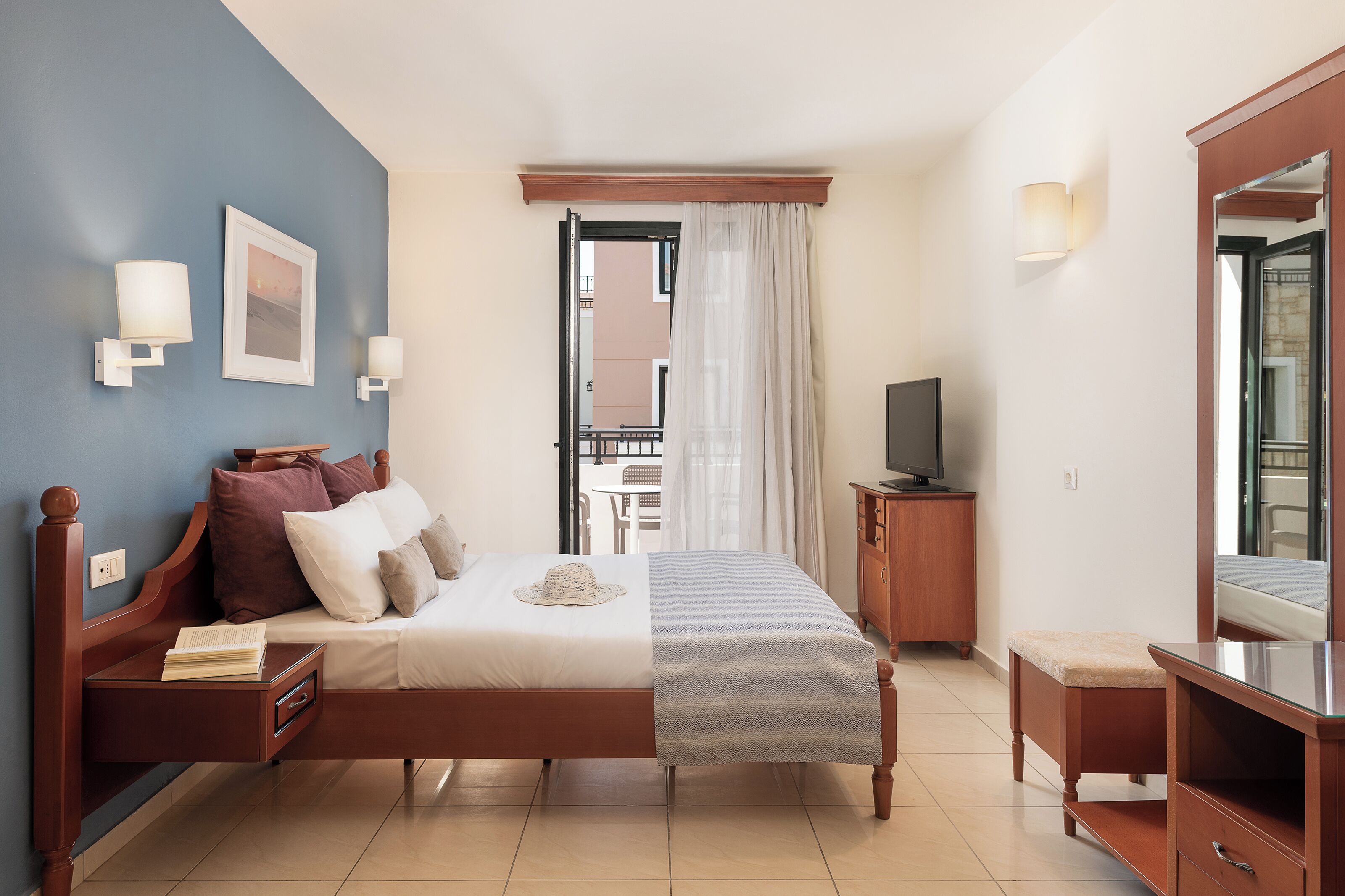A bedroom with a bed, bedside tables, a TV, and a mirror.