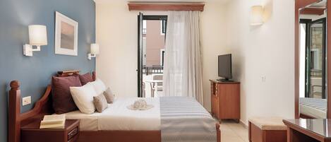 A bedroom with a bed, bedside tables, a TV, and a mirror.