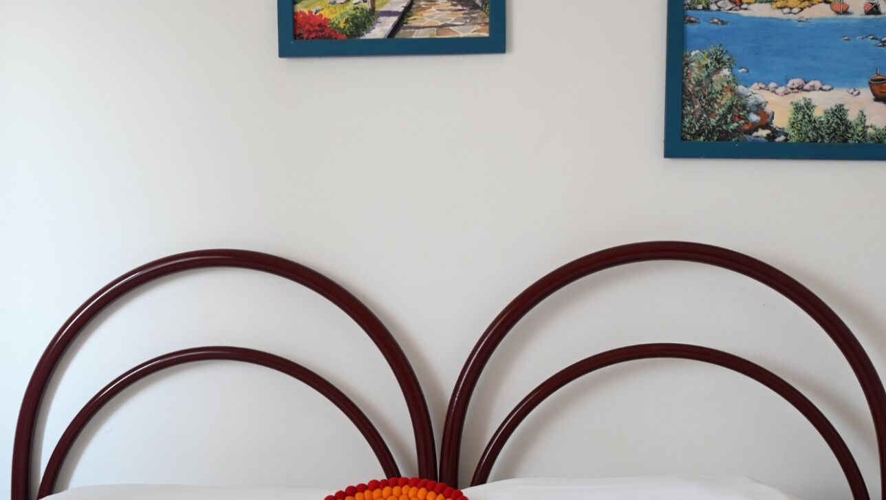 A bed with a white headboard and a decorative pillow.