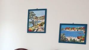 Ein Bett mit einem Regenbogenkissen, zwei gerahmte Bilder an der Wand und ein Holzkopfstück.