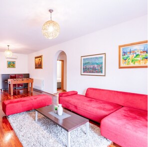 A modern living room with a red sofa, a coffee table, and a foosball table. There are paintings on the walls and a chandelier. - Mediterranean Villa with a private pool, Dubrovnik (Rožat)