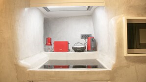 Pequeña cocina con microondas, tostadora y cafetera sobre una encimera blanca.