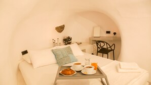 Habitación de hotel con cama, bandeja de desayuno, una silla y un pequeño rincón de cocina.