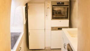 Una cocina compacta con armarios blancos, horno integrado y microondas.