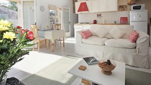 Ein gemütliches Wohnzimmer mit einem weißen Sofa, einem Couchtisch und einem Essbereich mit Tisch und Stühlen.
